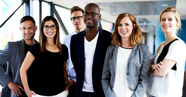 Group of young executives standing, smiling at camera and posing for picture